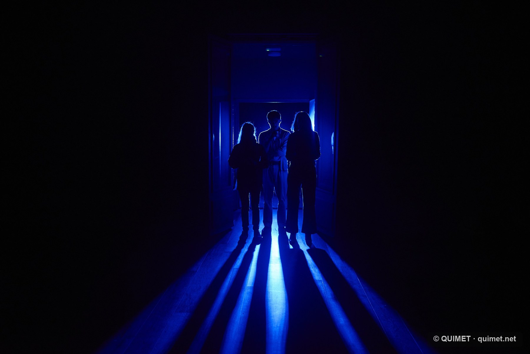 Siluetes teatrals en un passadís de llum blava